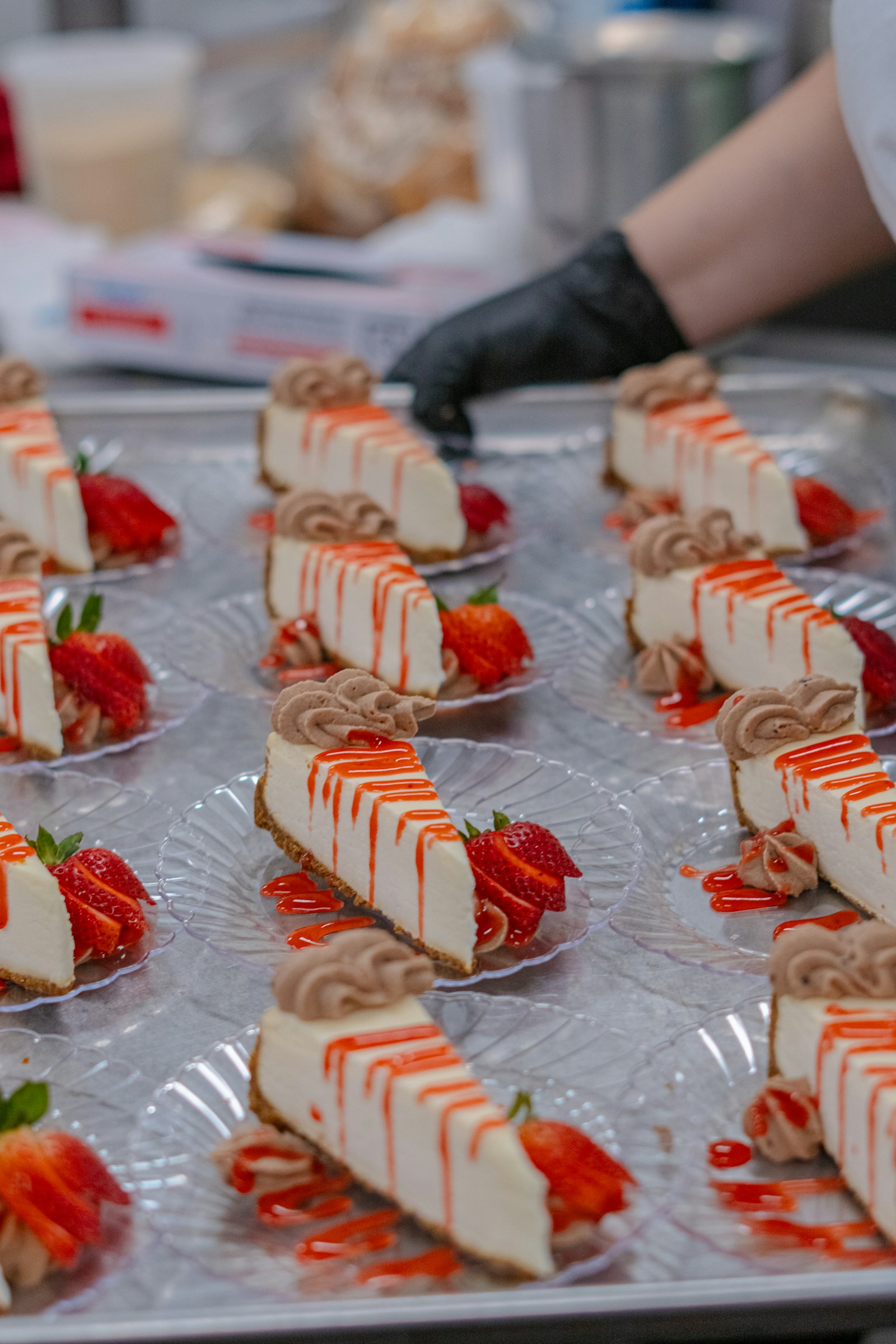 Pastry team finishing trays of strawberry cakes in a clean professional kitchen